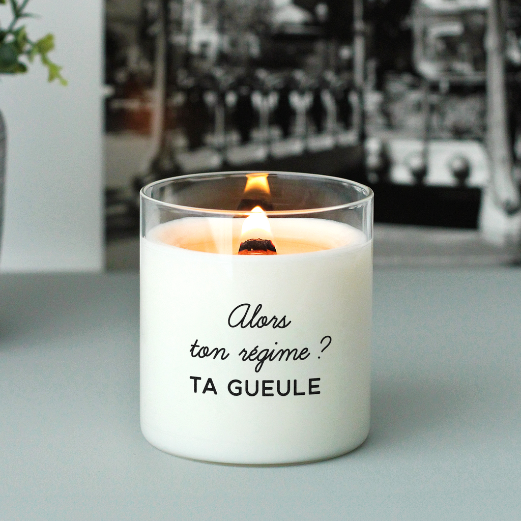 Bougie allumée avec le message "Alors ton régime ? TA GUEULE", posée sur une table gris clair, en arrière-plan noir et blanc, parfaite comme idée cadeau décalée à message sarcastique ou accessoire déco de cuisine avec humour.