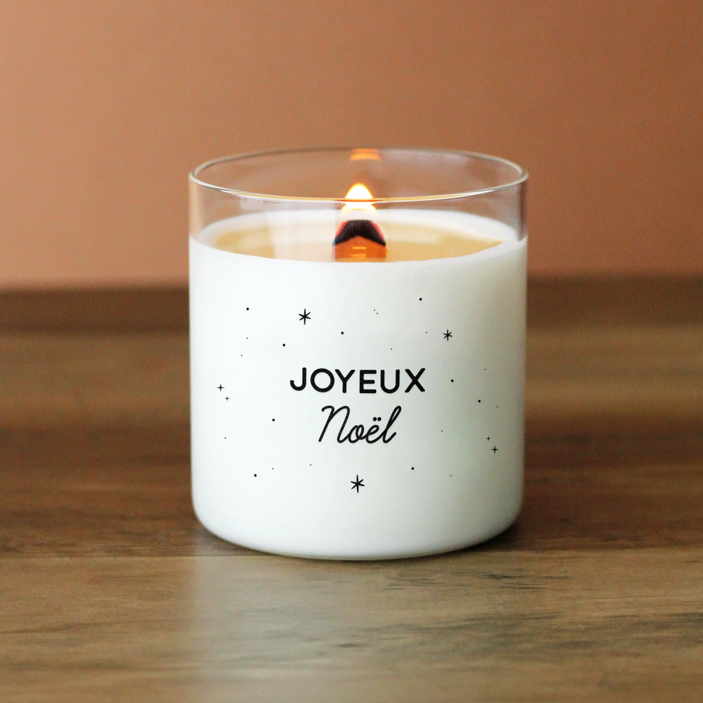 Bougie blanche avec le message « Joyeux Noël » entouré de petites étoiles noires. Parfaite pour une ambiance festive, traditionnelle et chaleureuse pendant les fêtes.