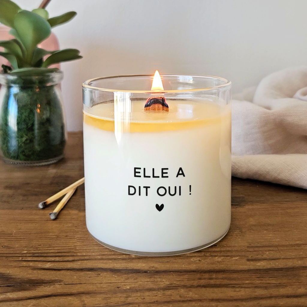 Bougie blanche avec le message « Elle a dit oui ! » et un petit cœur noir. Cadeau romantique à offrir à une fiancée pour célébrer ses fiançailles.