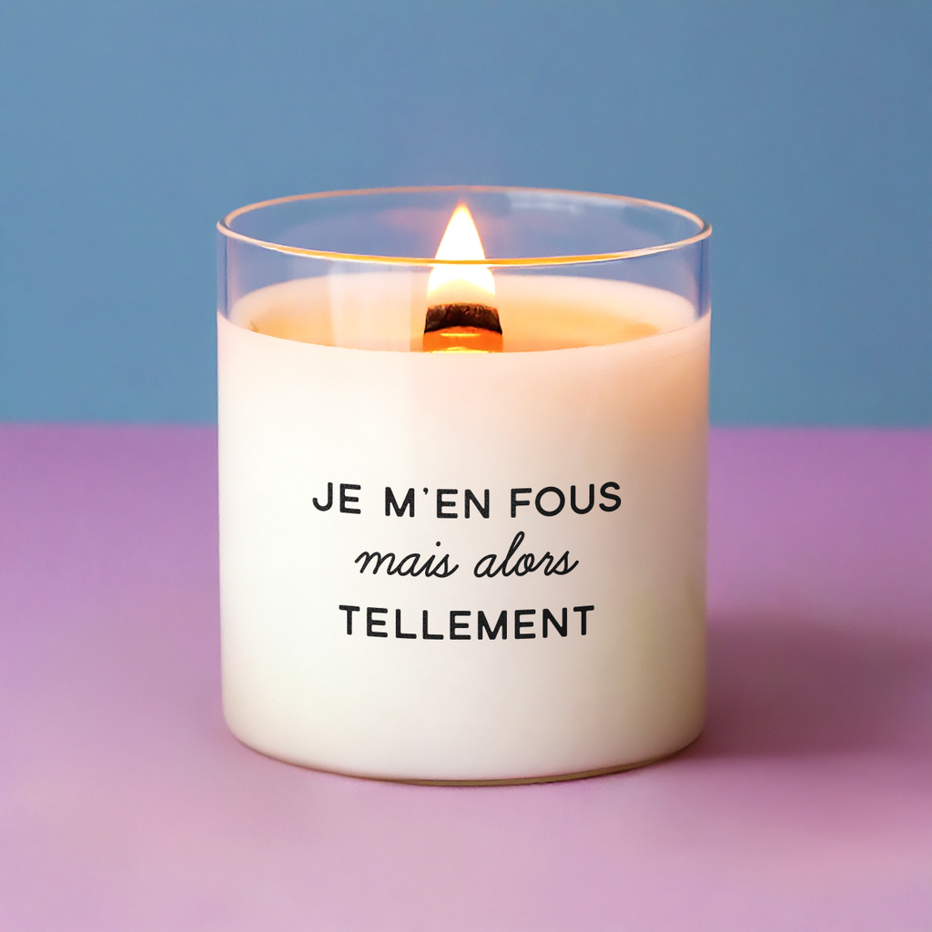 Bougie allumée avec l’inscription "Je m’en fous mais alors tellement", posée sur un fond rose et bleu, parfaite comme cadeau drôle ou message d’humeur désinvolte.