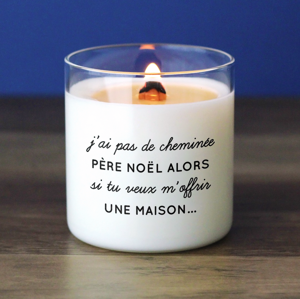 Bougie blanche avec le message "J’ai pas de cheminée Père Noël, alors si tu veux m’offrir une maison...", parfaite comme cadeau drôle de Noël.